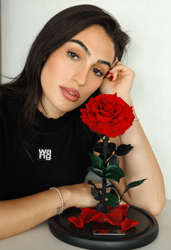 Woman posing with a preserved red rose on a black display base