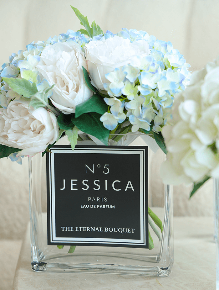 Everlasting mixed eden blooms, perfect for gifts to loved ones. The beautiful flowers, with hues of white, blue, green, and hints of yellow are encased in a beautiful sleek rectangular glass vase, with a personalised label placed on the middle. 