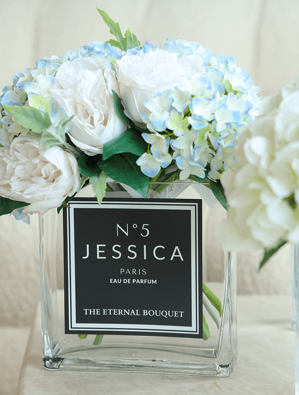 Everlasting mixed eden blooms, perfect for gifts to loved ones. The beautiful flowers, with hues of white, blue, green, and hints of yellow are encased in a beautiful sleek rectangular glass vase, with a personalised label placed on the middle. 