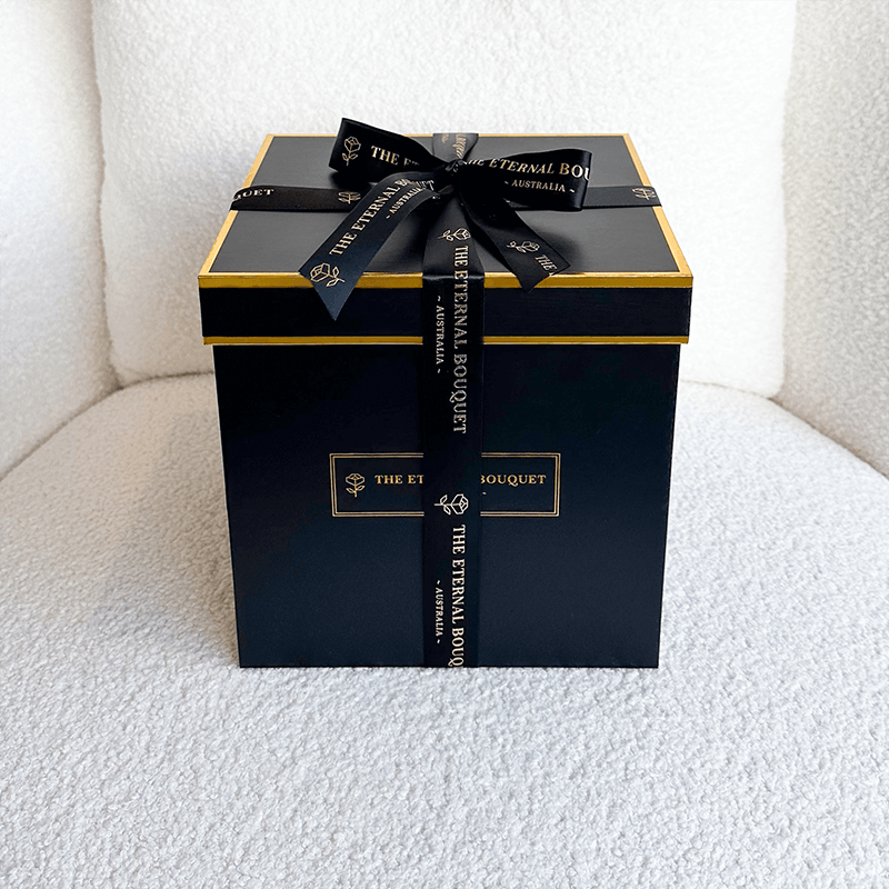 A sleek and elegant black gift box with gold accents and a luxurious black ribbon, featuring 
