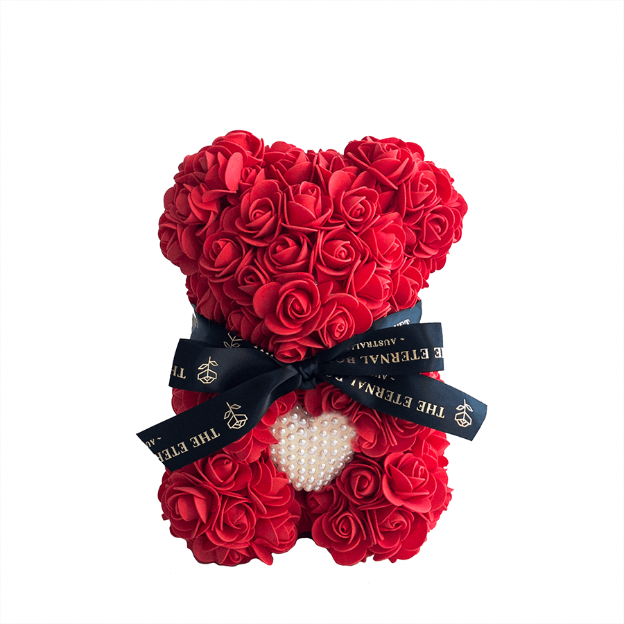 A handcrafted everlasting red rose teddy bear from The Eternal Bouquet, adorned with a luxurious black ribbon featuring gold branding and a charming pearl heart detail at the center. Elegant and eye-catching, this unique floral arrangement makes the perfect romantic gift for anniversaries, Valentine's Day, or as a heartfelt surprise to show everlasting love.