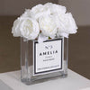A luxurious arrangement of elegant white peonies from The Eternal Bouquet, beautifully displayed in a clear glass square vase. The vase features a minimalist white label with black borders, personalised, adding a chic, designer-inspired touch. This everlasting flower arrangement is perfect for sophisticated gifting, offering a timeless and elegant statement.