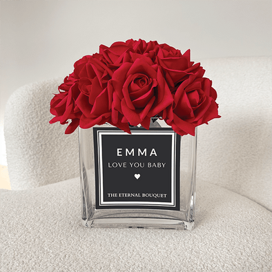 Beautiful red everlasting roses, encased in a sleek rectangular glass vase, with a personalised label. 