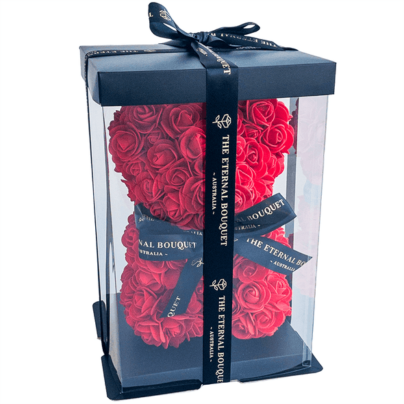 A luxurious red rose teddy bear from The Eternal Bouquet, beautifully encased in a clear display box and topped with a black ribbon featuring elegant gold branding. This eye-catching, handcrafted gift combines charm and sophistication, making it a memorable keepsake for romantic gestures, proposals, or milestone celebrations. A timeless symbol of love that never fades.