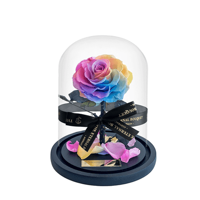 A vibrant everlasting rainbow rose elegantly displayed inside a clear glass dome with a black base. The arrangement is finished with a black ribbon that reads 'The Eternal Bouquet', adding a luxurious touch to this timeless floral keepsake. he perfect gift to give to your loved ones. 