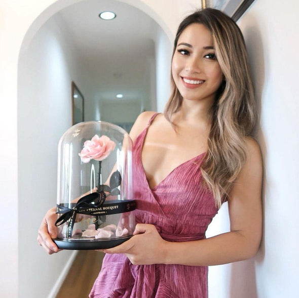A Beautiful Girl holding a Long Lasting Light Pink Rose in a glass dome 